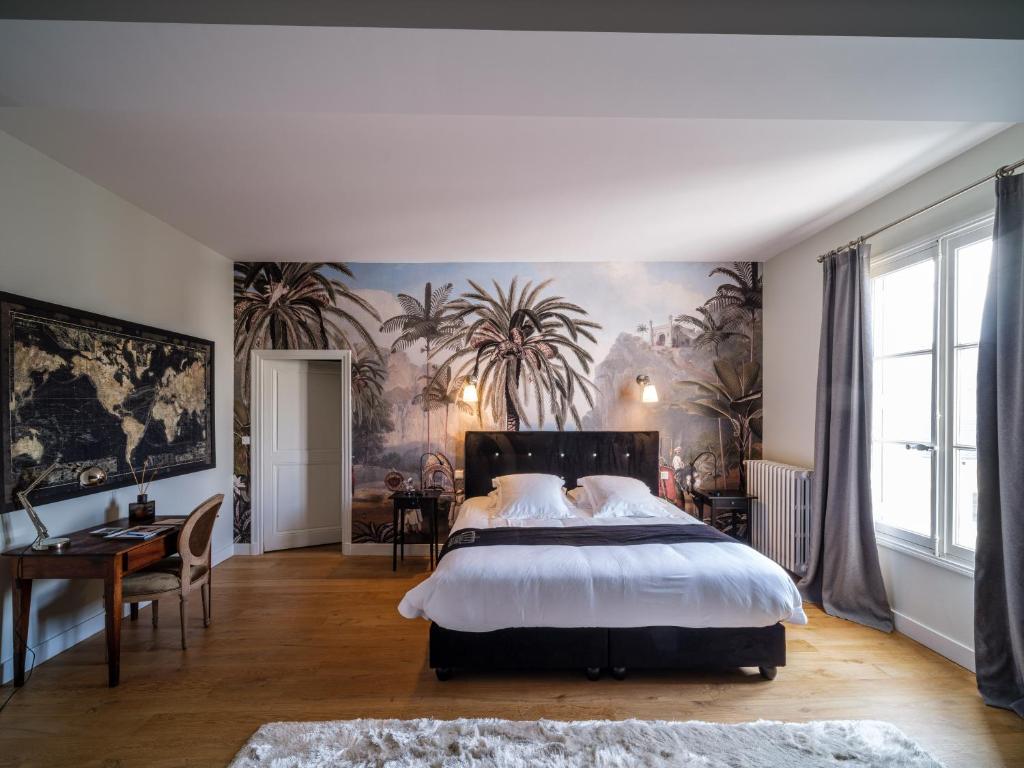 Aux Marquises في سوموور: غرفة نوم بسرير كبير عليها لوحة على الحائط