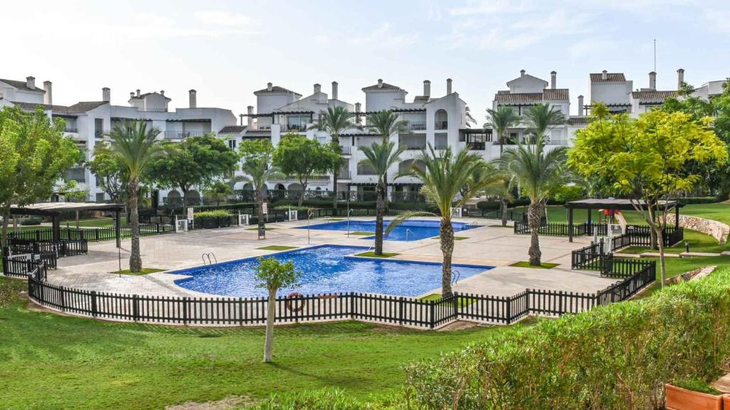 un complejo con piscina y palmeras en La Torre Golf Resort en Roldán