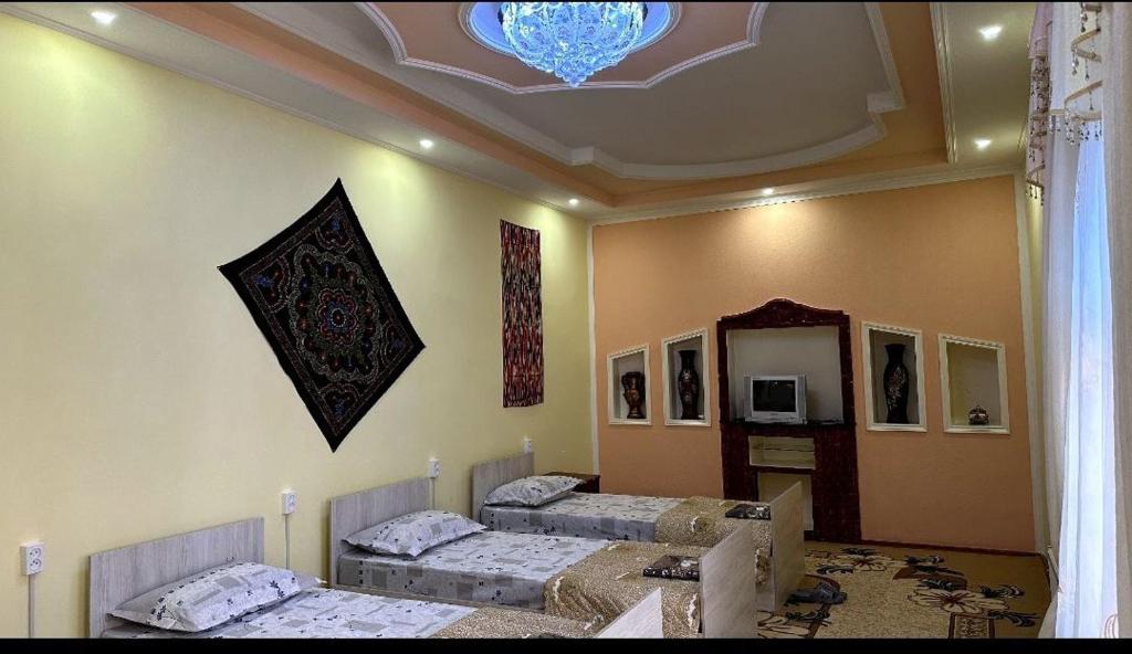 a room with three beds in it with a ceiling at Orzu Guest House in Bukhara
