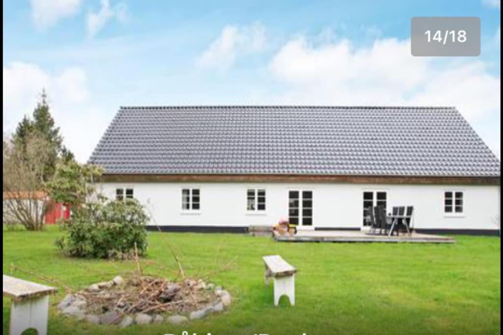 a white house with a large yard with a green lawn at Dejligt stort hus med spa in Ålbæk