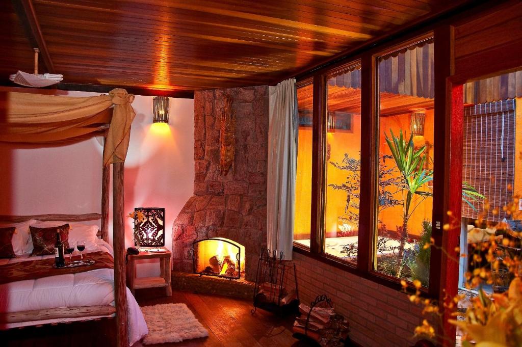 1 dormitorio con 1 cama y chimenea en una habitación en Pousada Recanto Da Serra, en Visconde De Maua