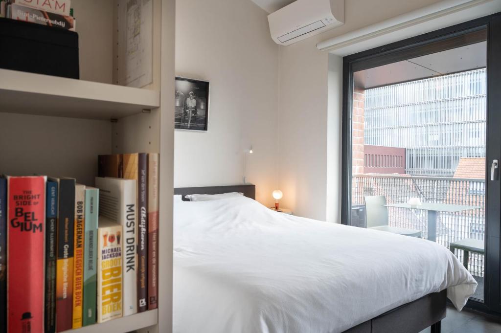 um quarto com uma cama e uma estante de livros com livros em Designflats Gent em Gent