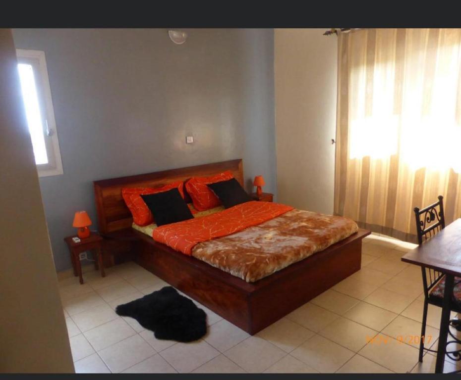 ein Schlafzimmer mit einem Bett mit orangefarbener Bettwäsche und einem Fenster in der Unterkunft Résidence H in Jaunde