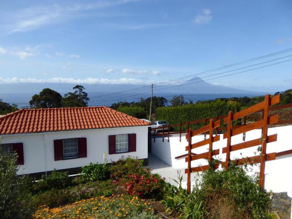 Casa blanca con techo rojo y valla en Azorean Cottage São Jorge en Urzelina