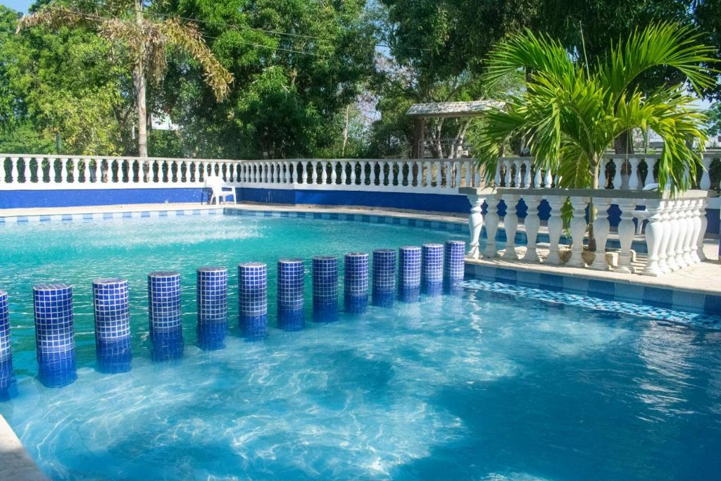 a swimming pool with a white fence and blue at Hotel Palmas del Río Mompox in Mompos