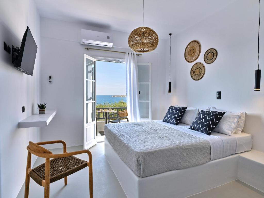 a white bedroom with a bed and a chair at Paros Five Senses in Parikia