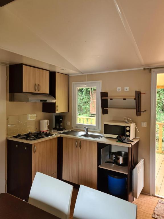 małą kuchnię z drewnianymi szafkami i oknem w obiekcie Mobil Home Camiers w mieście Camiers