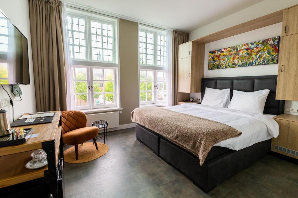 a bedroom with a bed and a desk and windows at Hotel Inn Naeldwyk in Naaldwijk