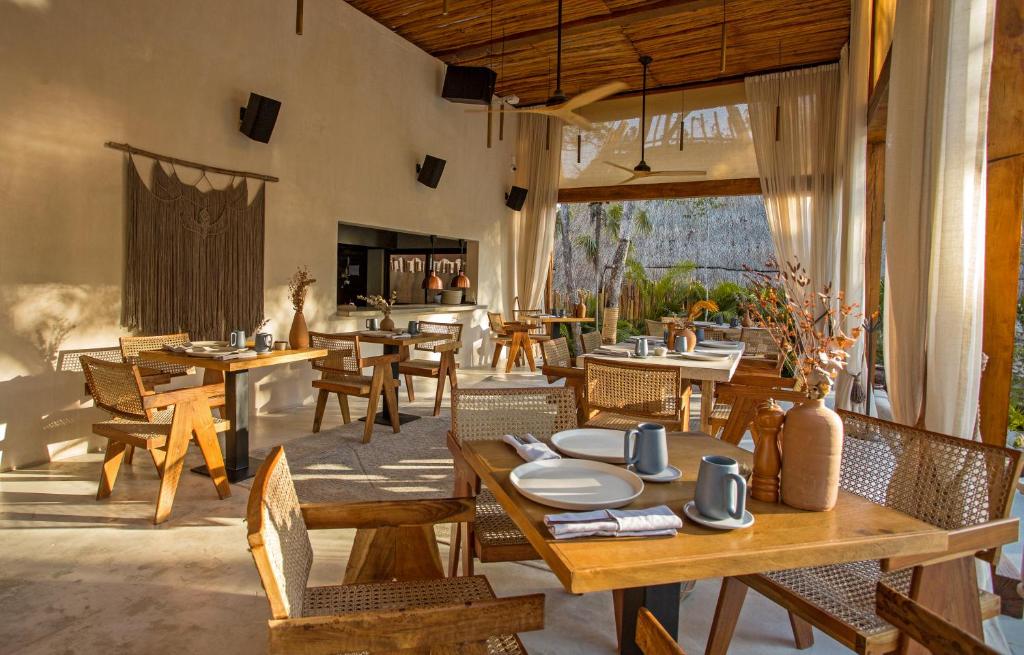a restaurant with wooden tables and chairs and a patio at Hotel Muaré & Spa Tulum in Tulum