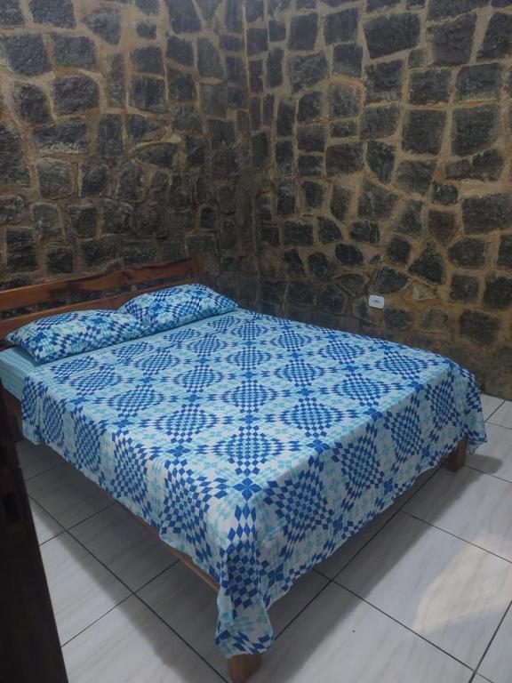 een blauw en wit bed in een stenen muur bij Chalé do corisco in Paraty