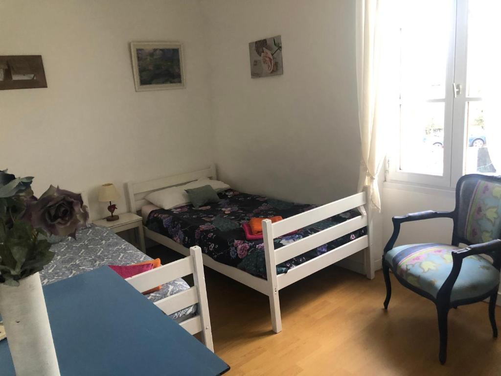 a bedroom with a bed and a table and a chair at Gîte des Roses in Oradour-Fanais