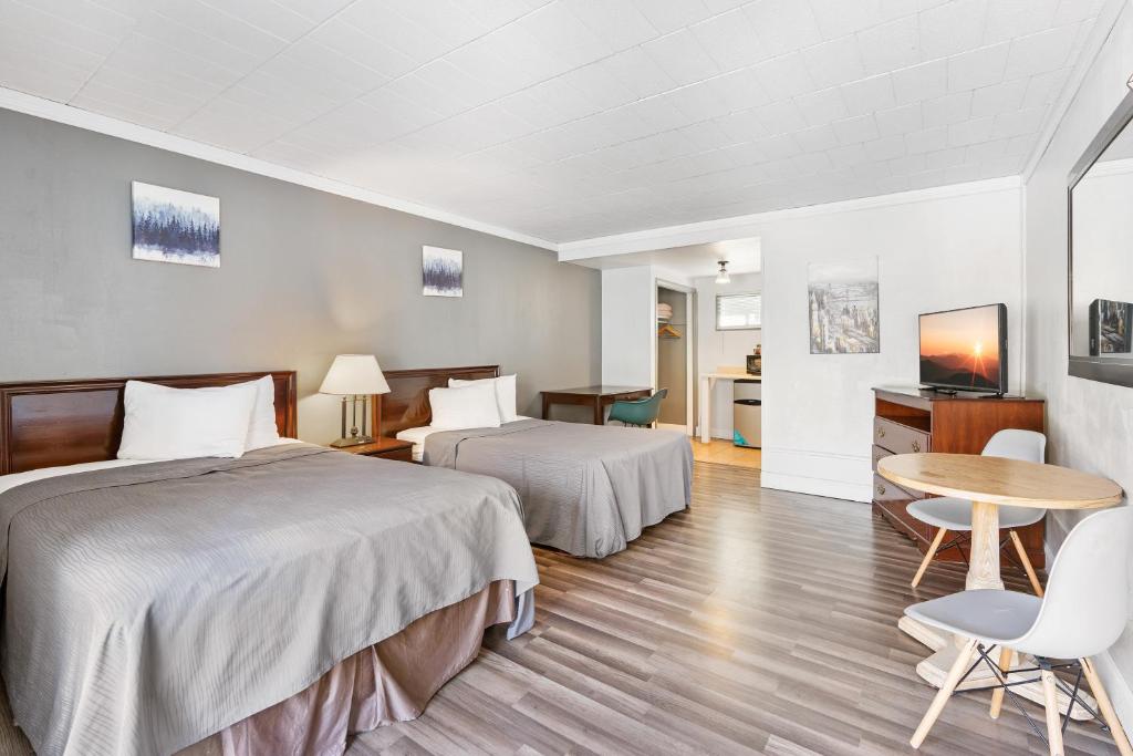 ハイランドフォールズにあるFairBridge Inn and Suites West Pointのベッド2台、テーブルと椅子が備わるホテルルームです。