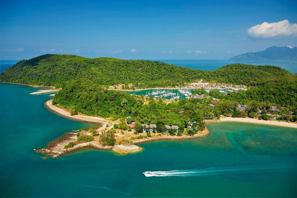 Rebak Island Resort & Marina, Langkawi في بانتايْ سينانج: جزيرة في المحيط مع قارب في الماء