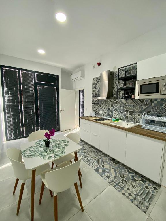 a white kitchen with a table and chairs and a counter at El Mosaico Apartment in Valencia