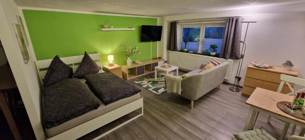 a living room with a couch and a green wall at Ferienwohnung Bergblick in Sebnitz