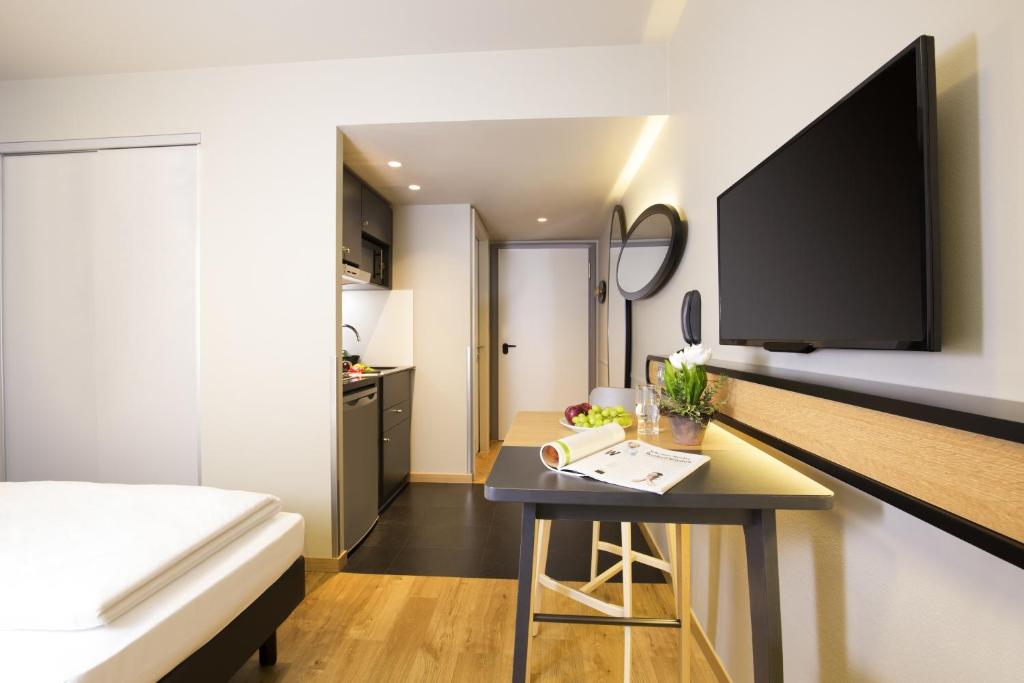 a room with a bed and a table with a tv at Aparthotel Adagio access München City Olympiapark in Munich