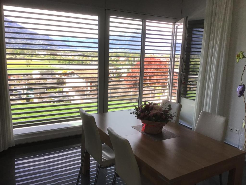 een eetkamer met een tafel, stoelen en ramen bij Moderno bilocale vista lago Maggiore in Gordola