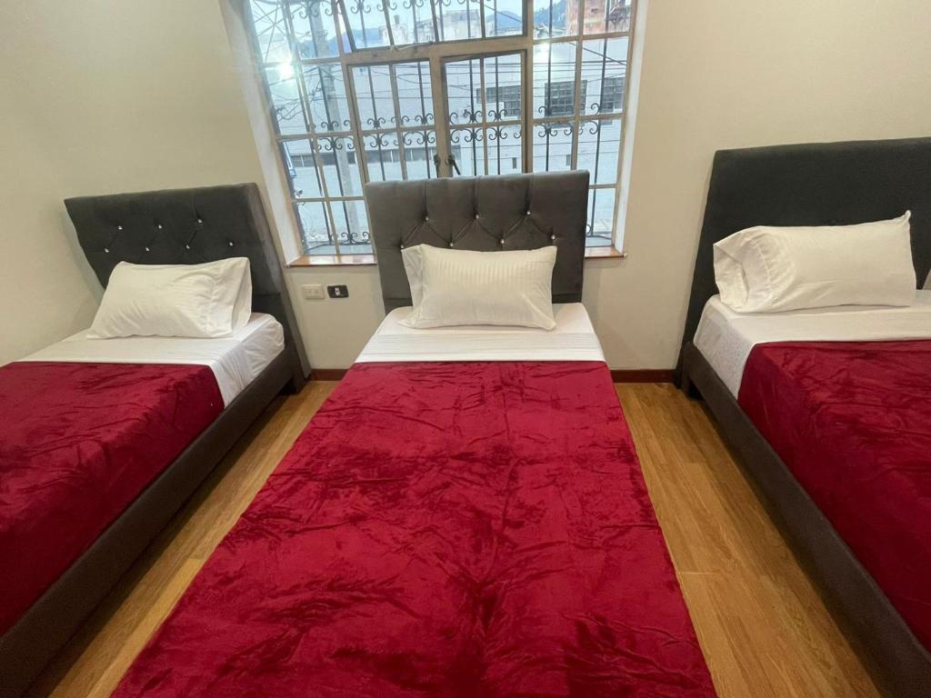 2 camas sentadas en una habitación con mantas rojas en Hotel Casa Morada FC, en Bogotá