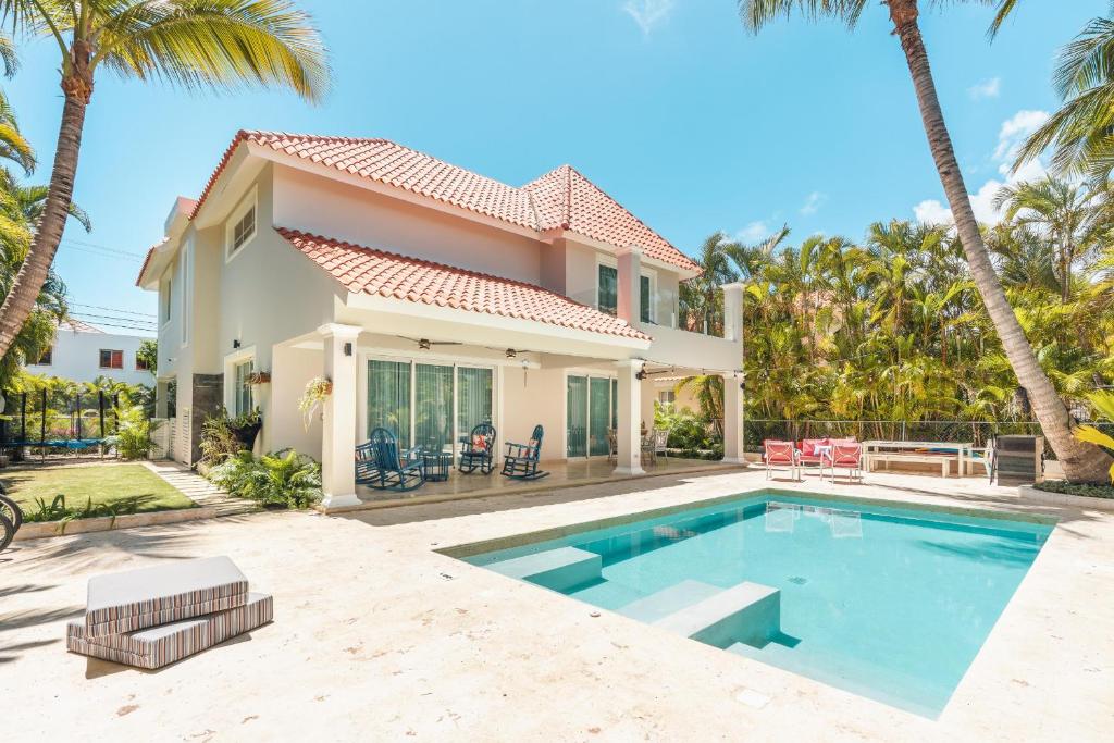 a house with a swimming pool and palm trees at Enjoy this modern pet and family friendly villa B6 in Punta Cana