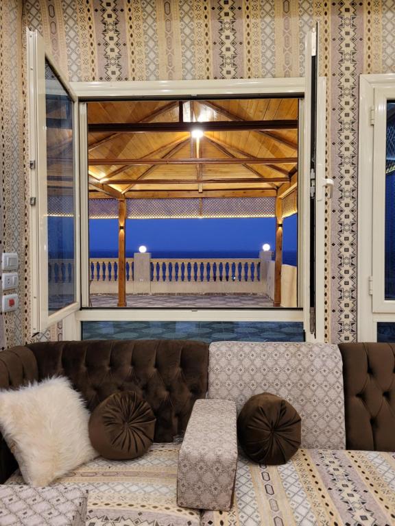 a living room with a couch and a large window at مون لايت Moon Light Villa in ‘Ezbet Sa‘dî Mugâwir