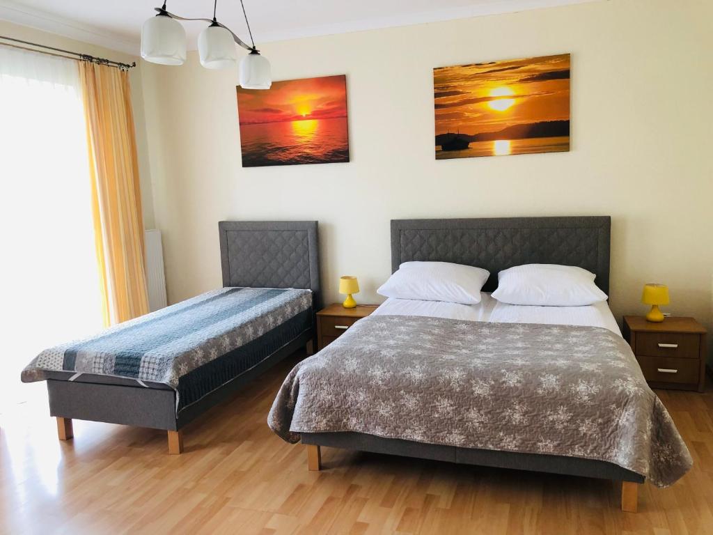 a bedroom with two beds and two paintings on the wall at Dom Wypoczynkowy Olivia in Darlowko