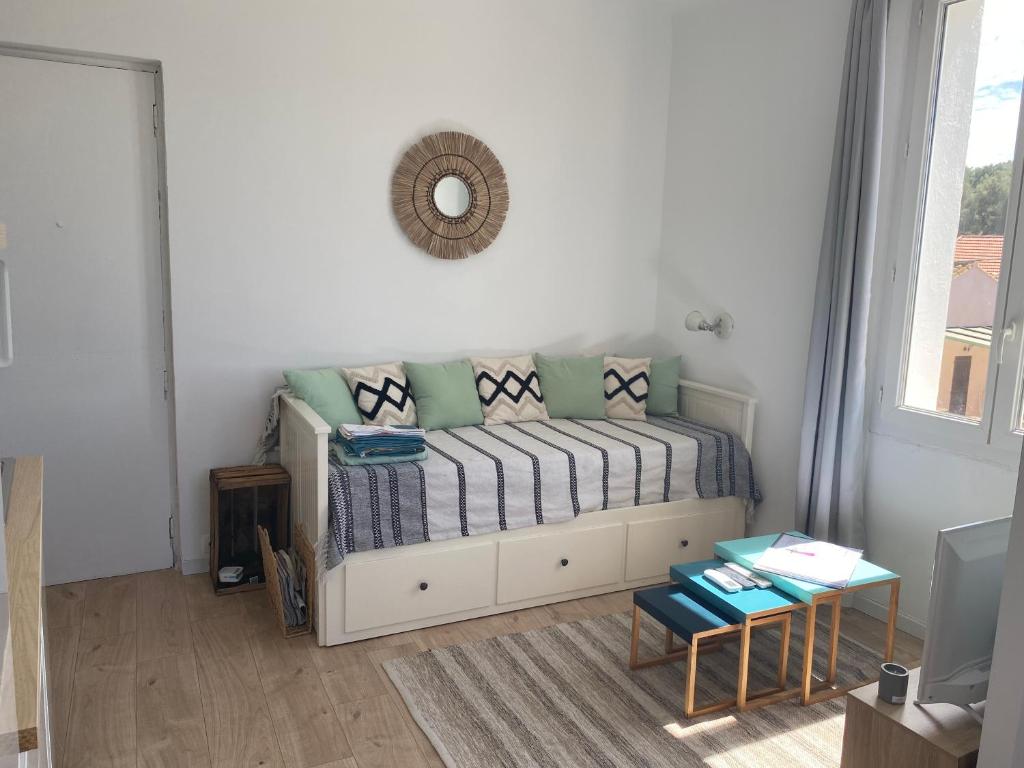 a living room with a bed with pillows and a mirror at Studio le Monroe les pieds dans l'eau 10 m de la mer in La Seyne-sur-Mer