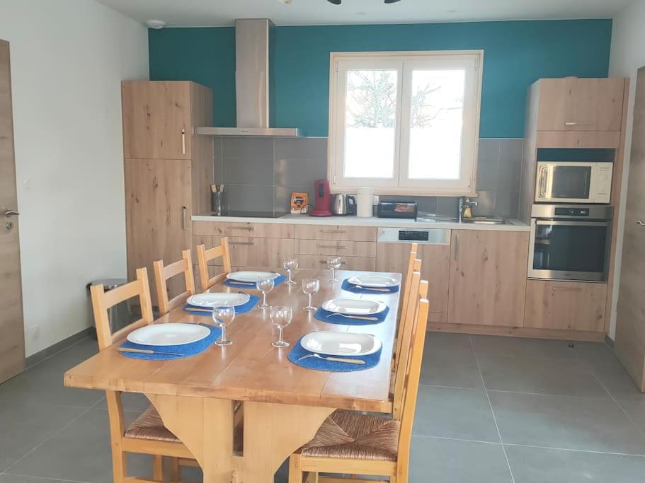 a kitchen with a wooden table with plates and wine glasses at Gîte à louer in Labergement-Sainte-Marie