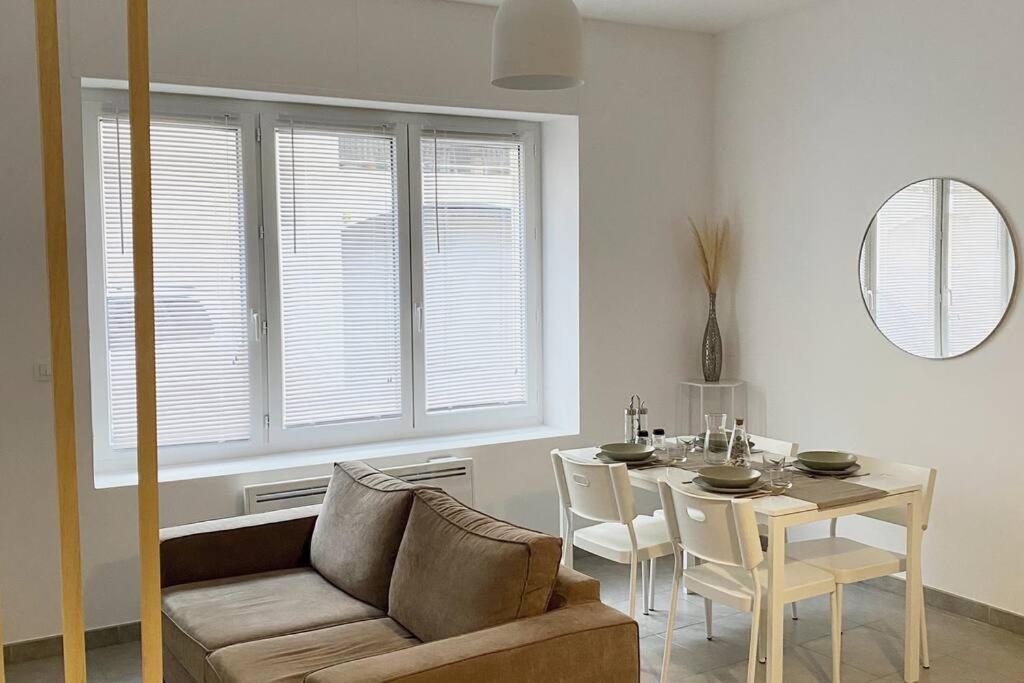 uma sala de estar com um sofá e uma mesa com cadeiras em Appartement Les Halles Narbonne em Narbona