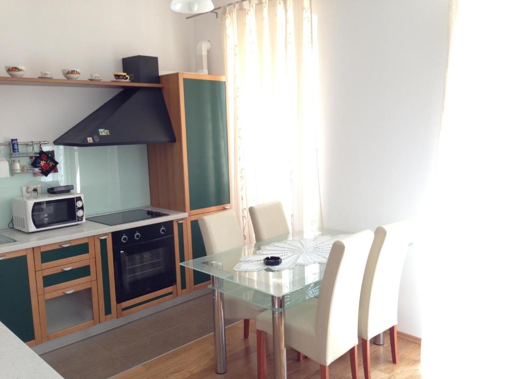 eine kleine Küche mit einem Glastisch und weißen Stühlen in der Unterkunft Apartment Duncovich in Cres