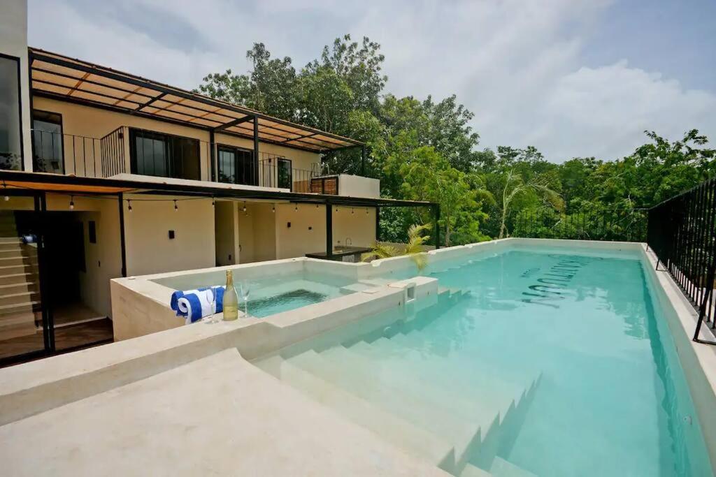 a large swimming pool in front of a house at Depto lujoso con jacuzzi privado, Piscina y jungle Gym in Tulum