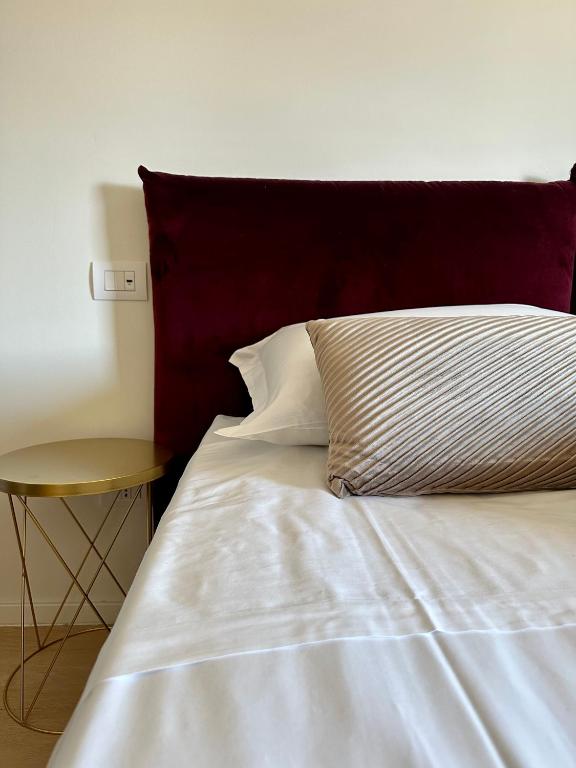 a white bed with a red headboard and a table at C House Rooms Lake in Peschiera del Garda