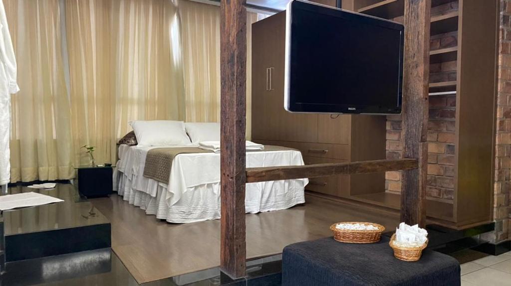 a room with a bed and a flat screen tv at Manferrari Hotel in Contagem