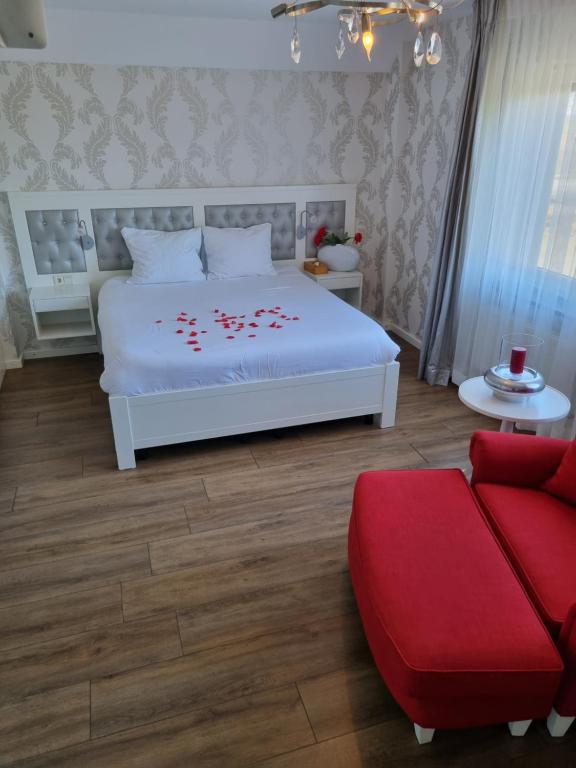 a bedroom with a white bed and a red couch at Hotel Restaurant Keizersberg in Elsendorp