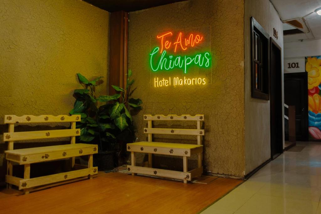 a restaurant with two benches in front of a neon sign at Hotel Makarios in Tuxtla Gutiérrez