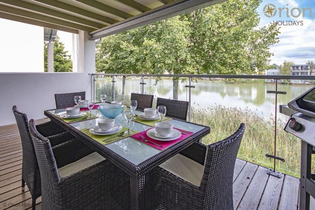 a table and chairs on a deck with a view of the water at Howells Mere 88, Tranquility P in Somerford Keynes