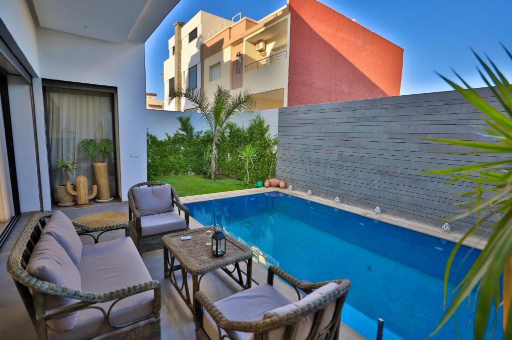 a pool with chairs and a table next to a building at Moon house in Ville Nouvelle