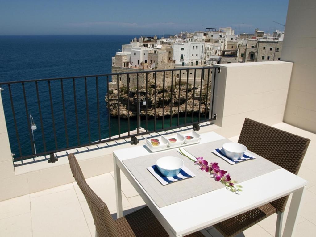 einen weißen Tisch und Stühle auf einem Balkon mit Meerblick in der Unterkunft Malù Bed&Breakfast in Polignano a Mare