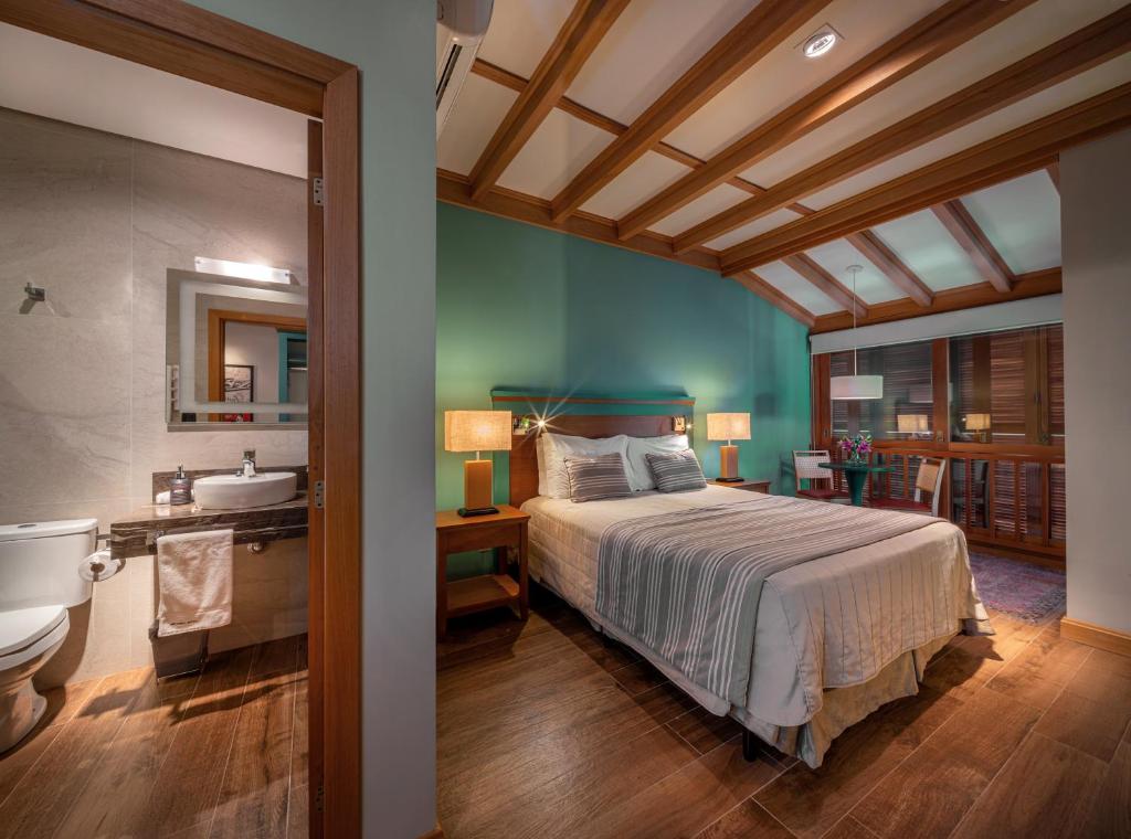 ein Schlafzimmer mit einem Bett und ein Badezimmer mit einem Waschbecken in der Unterkunft Hotel Britanico Express in Gramado