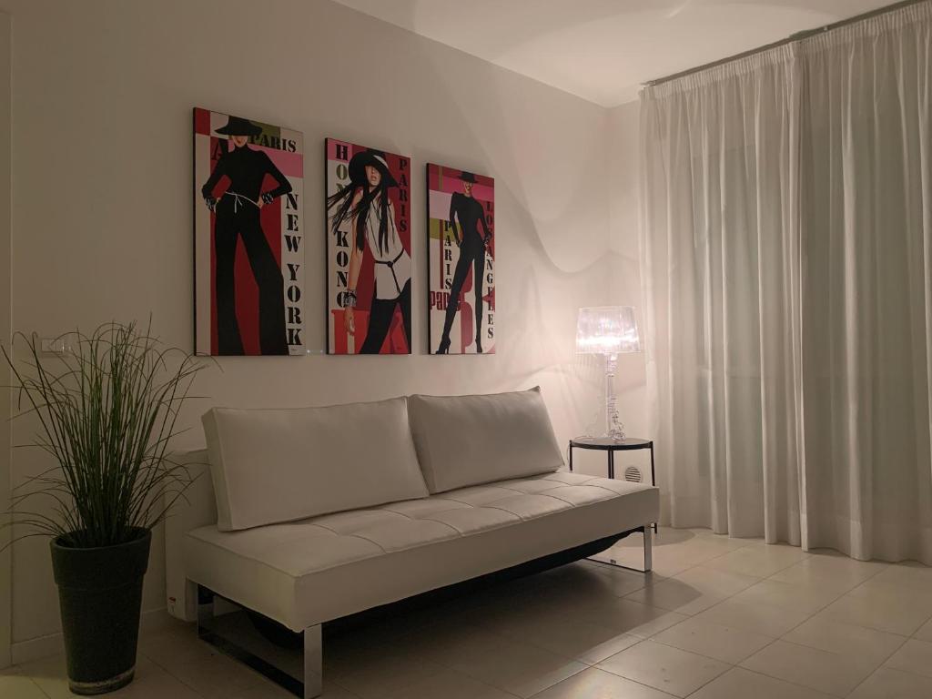 - un salon avec un canapé et des photos sur le mur dans l'établissement Poetto Apartment, à Quartu SantʼElena
