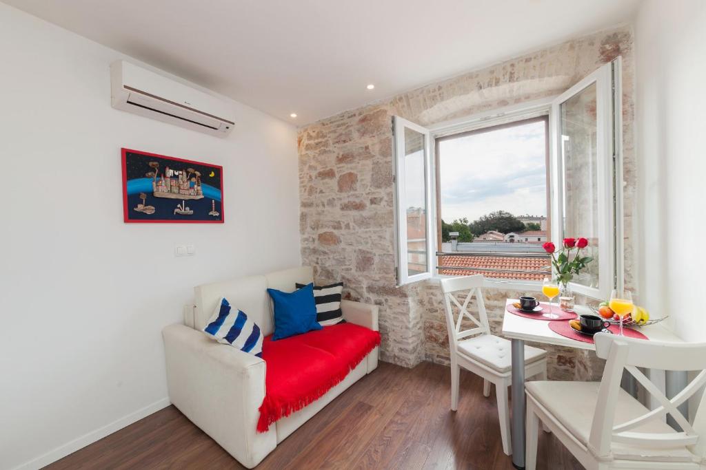 uma sala de estar com um sofá vermelho e uma mesa em Imperium Central Apartments Zadar em Zadar