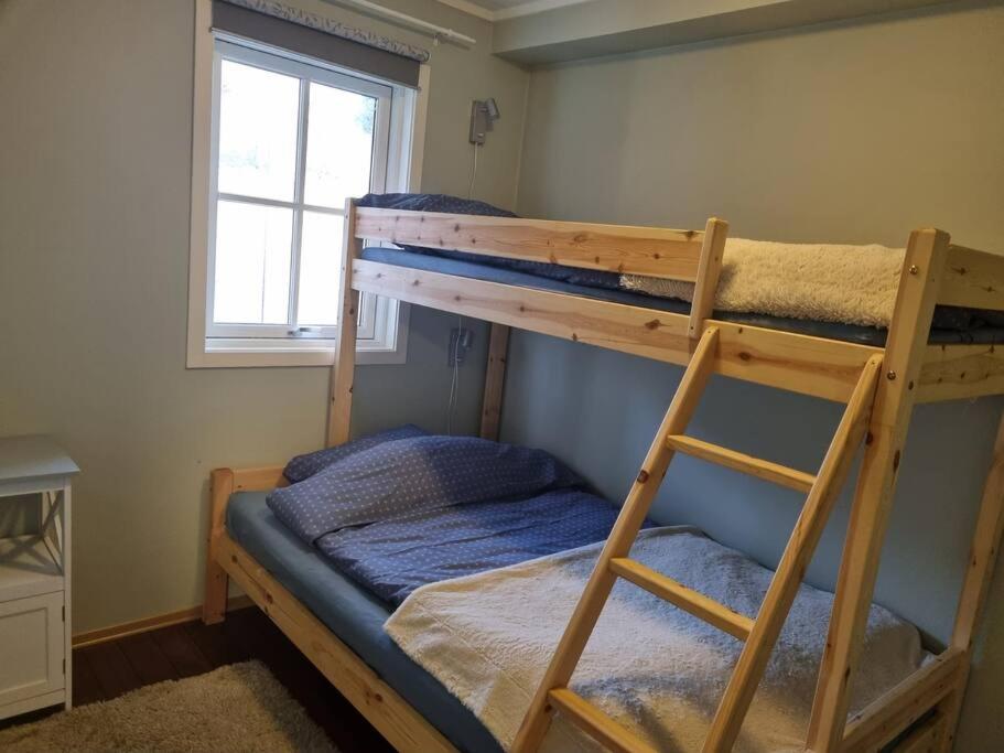 a bedroom with two bunk beds and a window at Sjøhus ved Tjeldsundet - House by the sea in Evenskjer