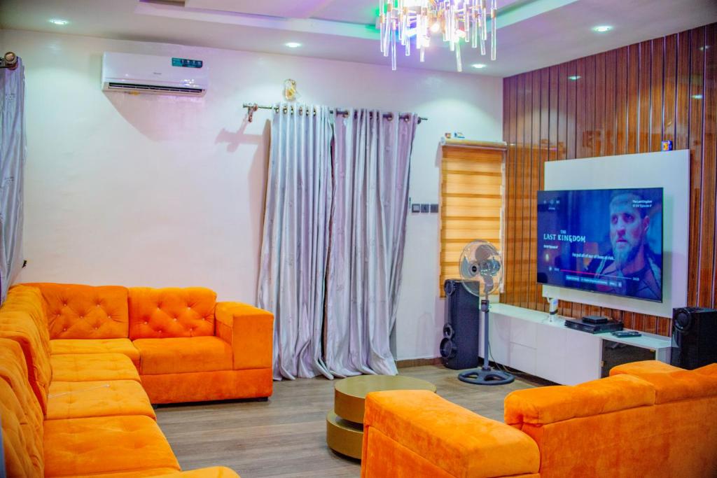 sala de estar con sofá naranja y TV de pantalla plana en Superb 2-Bedroom Duplex FAST WiFi+24Hrs Power, en Lagos