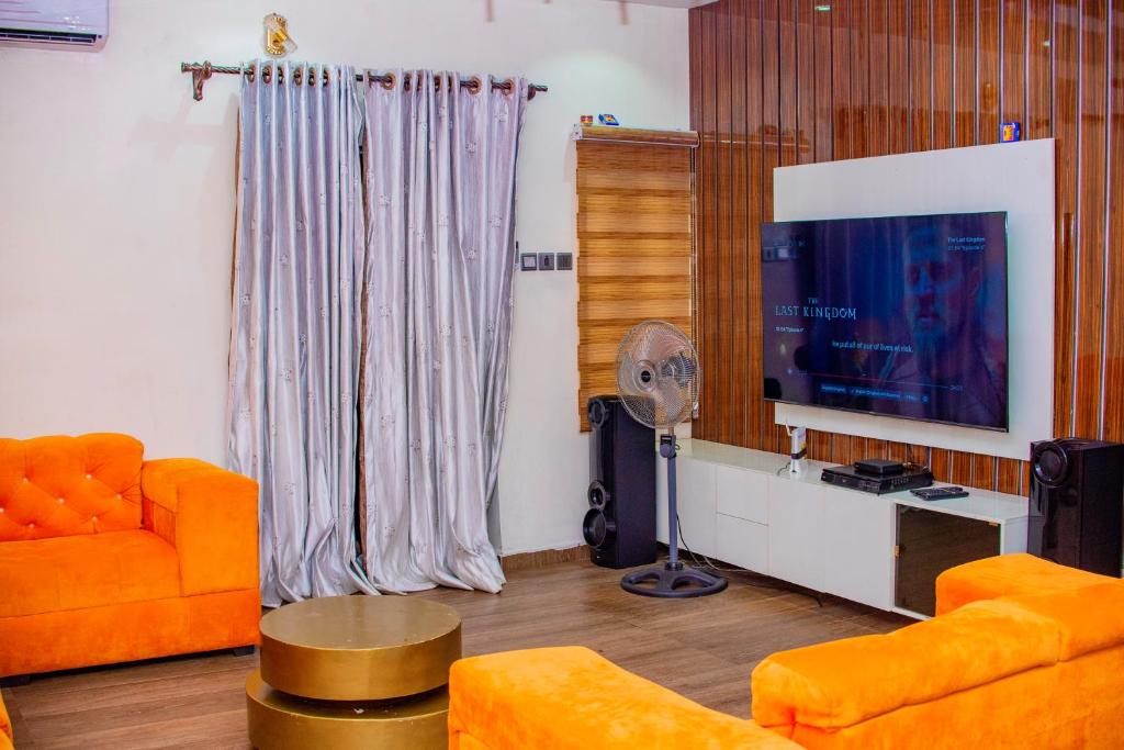 un soggiorno con mobili arancioni e TV a schermo piatto di Luxury 3-Bedroom Duplex FAST WIFI & 247Power a Lagos