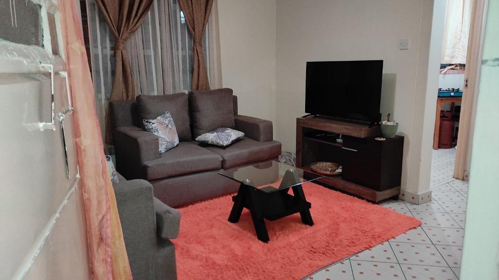 uma sala de estar com um sofá e uma televisão em Pearls Paradise em Nairobi
