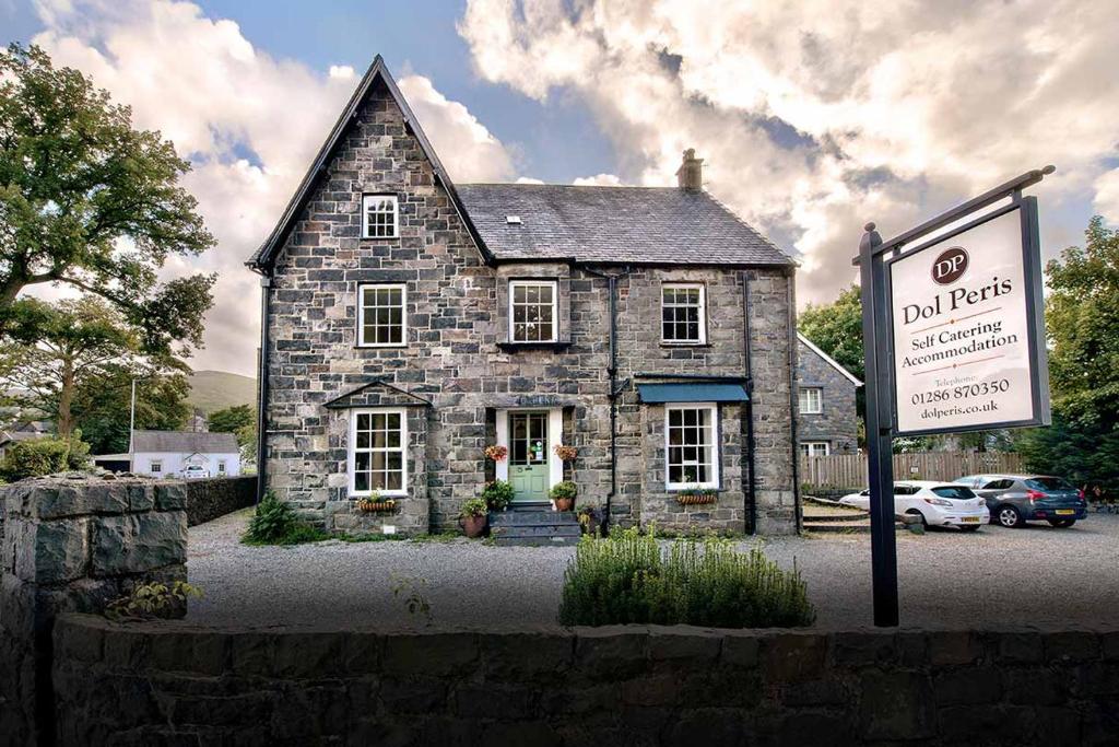 an old stone house with a sign in front of it at Dol Peris in Llanberis