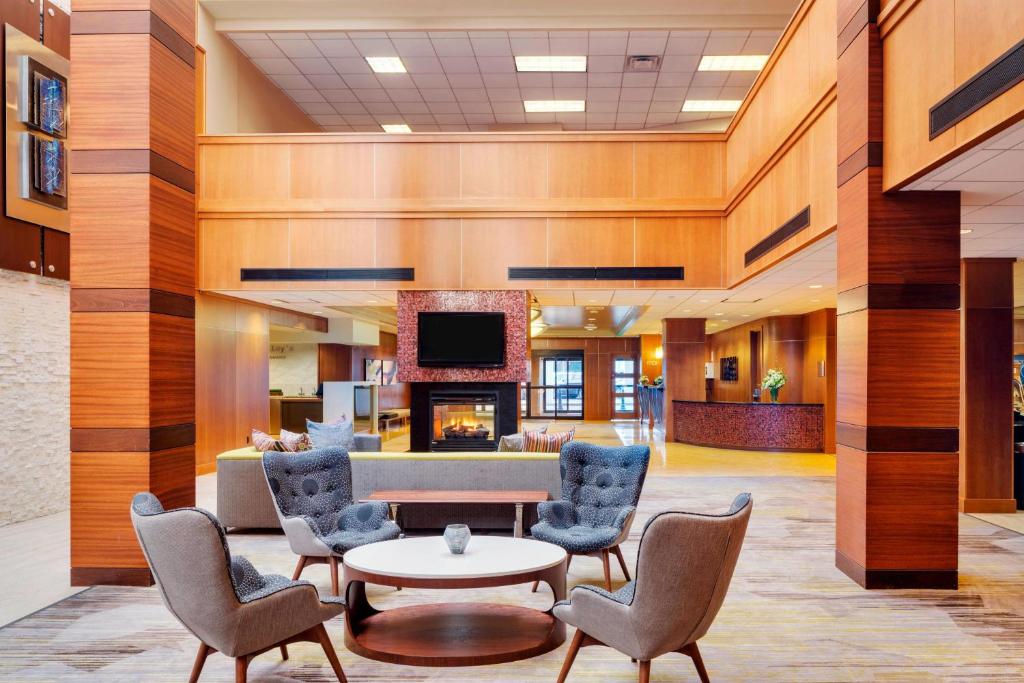 a lobby with chairs and a table and a fireplace at Courtyard by Marriott Boston Logan Airport in Boston