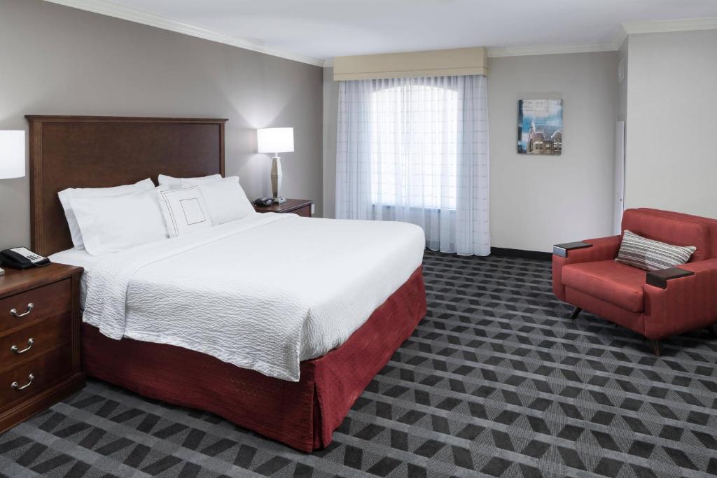 - une chambre avec un grand lit et une chaise rouge dans l'établissement TownePlace Suites Fort Worth Downtown, à Fort Worth