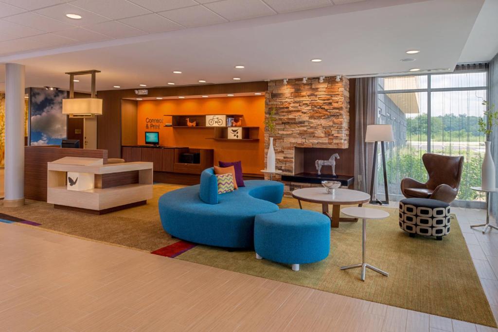 Fairfield Inn & Suites by Marriott Huntington في هنتنجتون: غرفة معيشة مع كراسي زرقاء وأريكة وطاولة