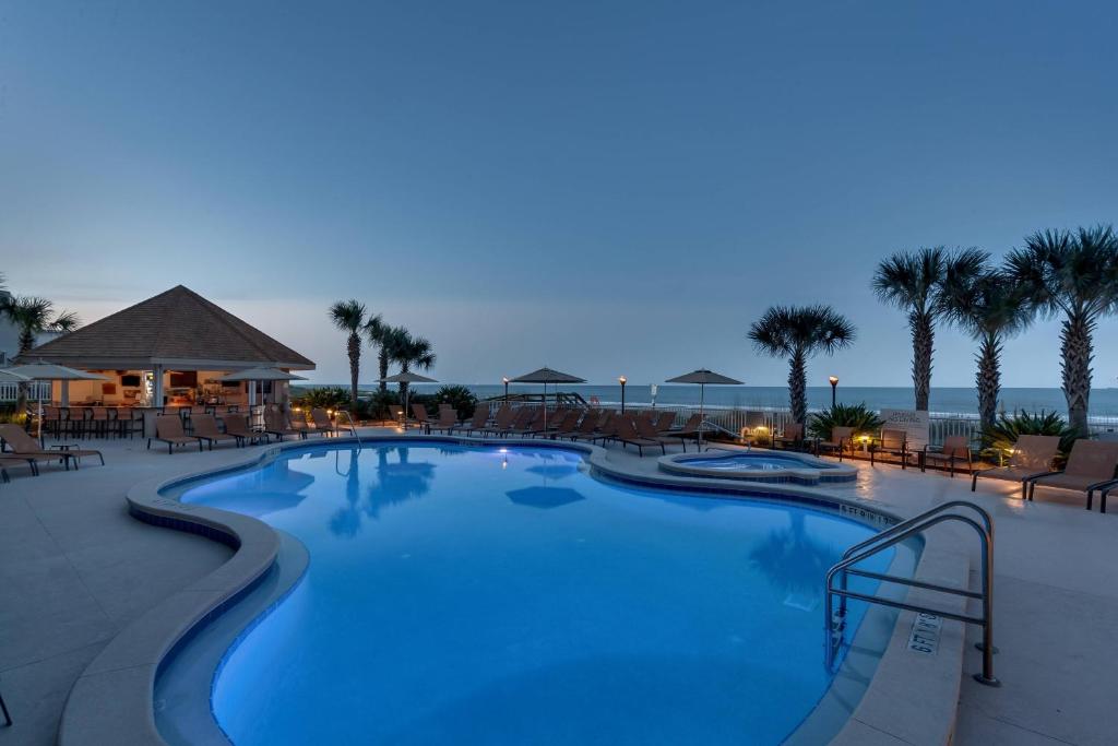 una gran piscina en un complejo por la noche en Courtyard by Marriott Jacksonville Beach Oceanfront, en Jacksonville Beach