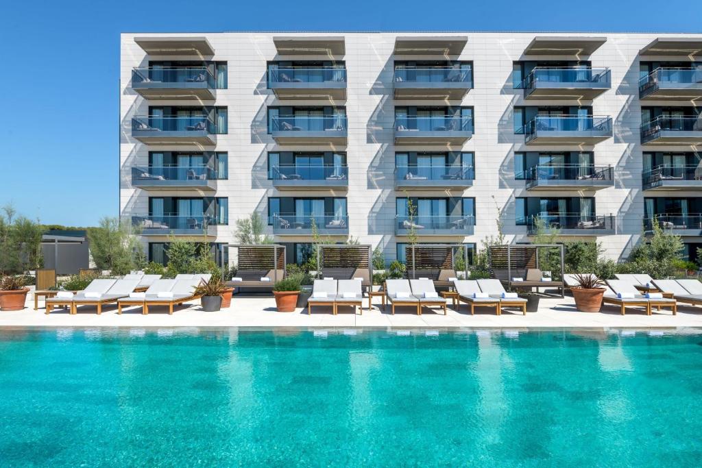 a swimming pool with lounge chairs and a building at Sabàtic Sitges Hotel, Autograph Collection in Sitges